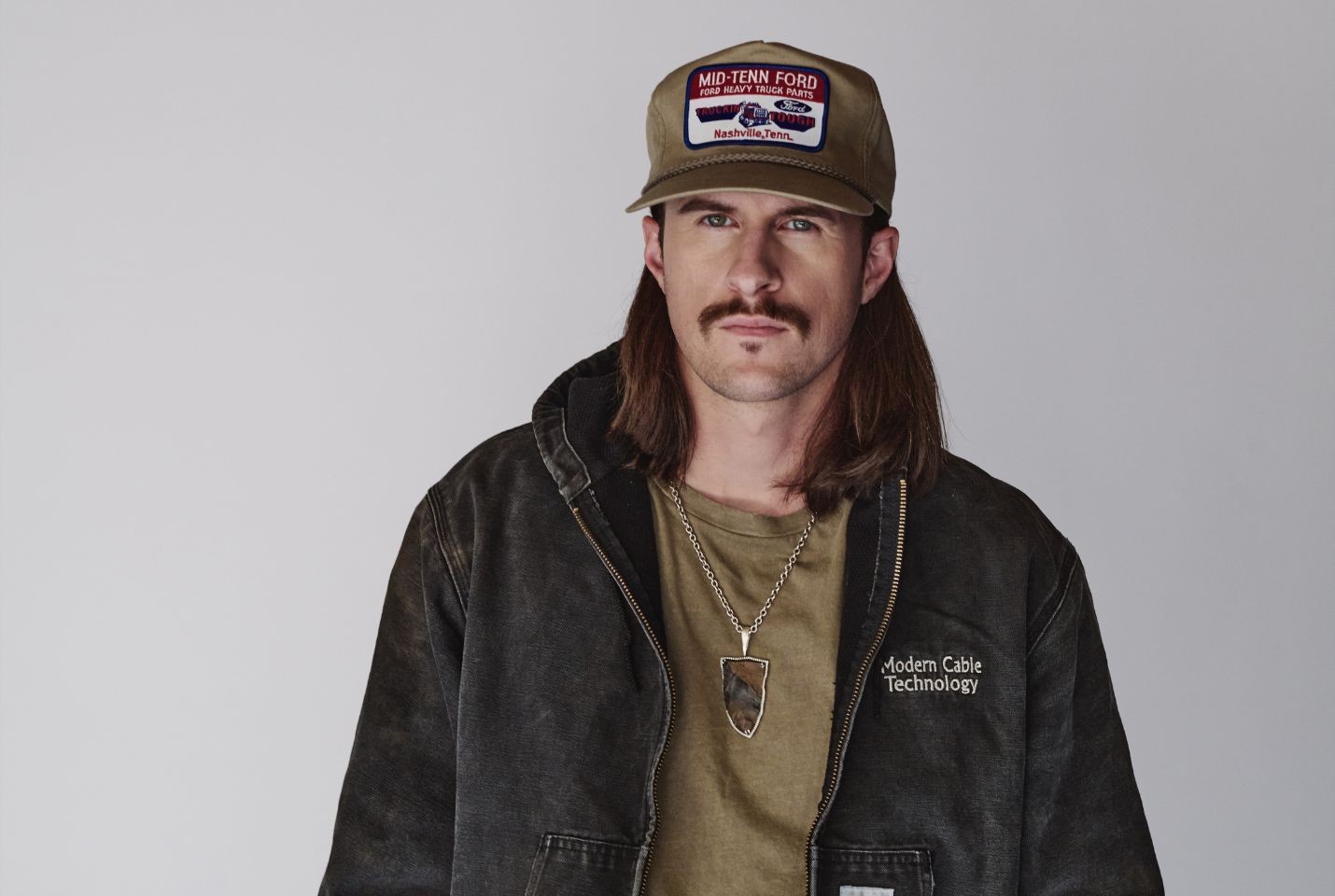 John Morgan wearing a green tshirt, black jacket, and green cap